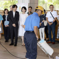 Crown Prince Akishino and Crown Princess Kiko on Sunday watch a student use a machine to clean the floor during their visit to a vocational training presentation by special education school students taking part in the National High School Arts Festival in the city of Saga. This year the festival was held at various venues in Saga Prefecture. The couple also listened to performances by visually impaired students. | POOL / VIA KYODO