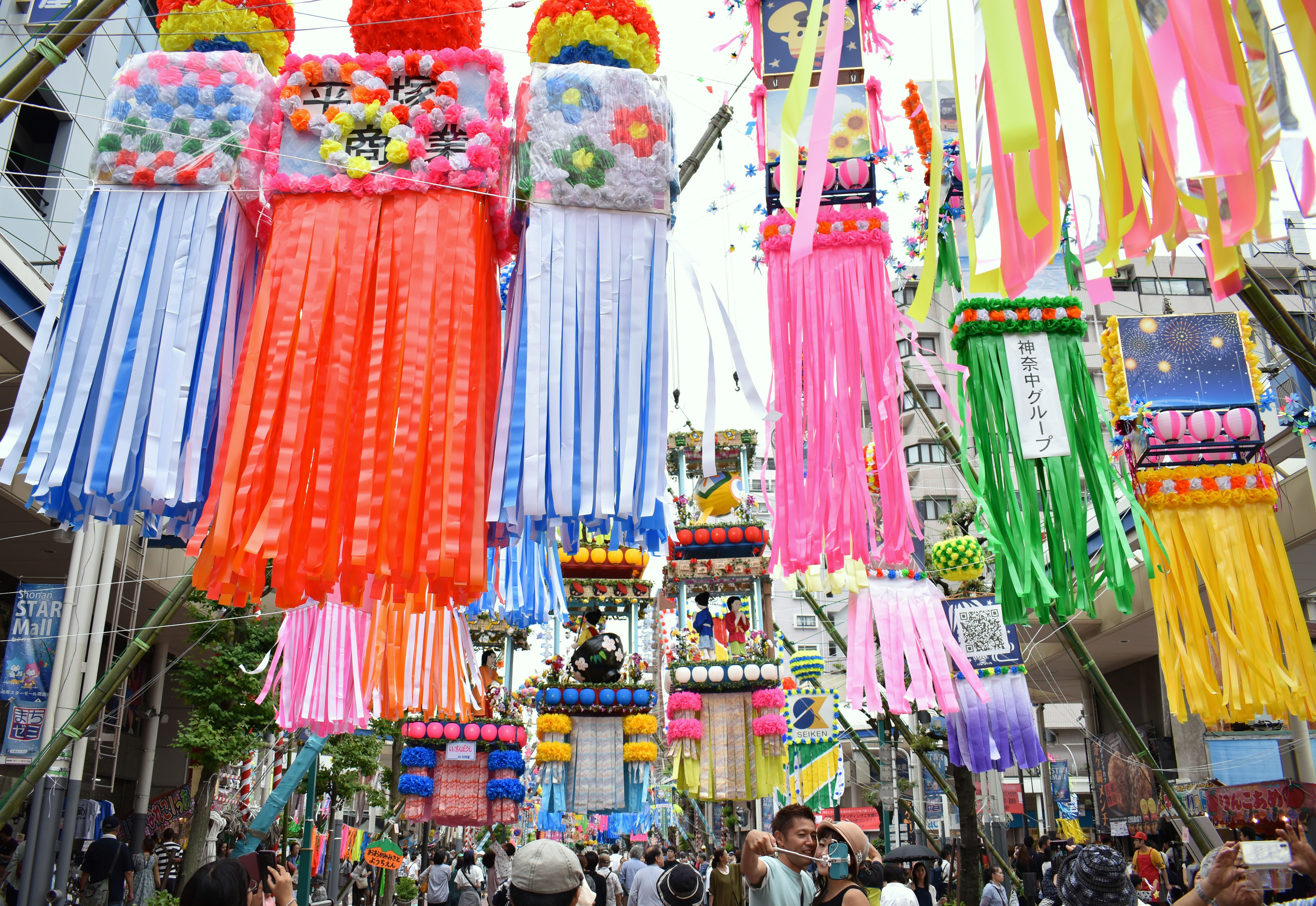 People walk under banners hung to celebrate the Tanabata star festival in Hiratsuka, Kanagawa Prefecture, on Friday. About 1.5 million visitors are expected to visit Hiratsuka during the three-day event through Sunday. The festival celebrates the reunion of the deities and lovers Orihime and Hikoboshi, who can only meet on the night of July 7. | SATOKO KAWASAKI