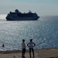 Men watch the cruise ship MS Empress of the Seas, operated by Royal Caribbean International, as it leaves the bay of Havana June 5. | REUTERS