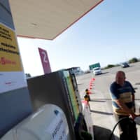 A placard reading \"Maximum limit 15 liters per filling\" is seen as a man fills up a car during a fuel strike, at a gas station in Lisbon Aug. 12. | REUTERS