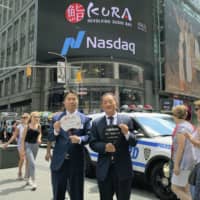Kura Sushi President Kunihiko Tanaka (right) poses for a photo in New York on Thursday, the same day the U.S. arm of his sushi chain debuts on the Nasdaq. | KYODO