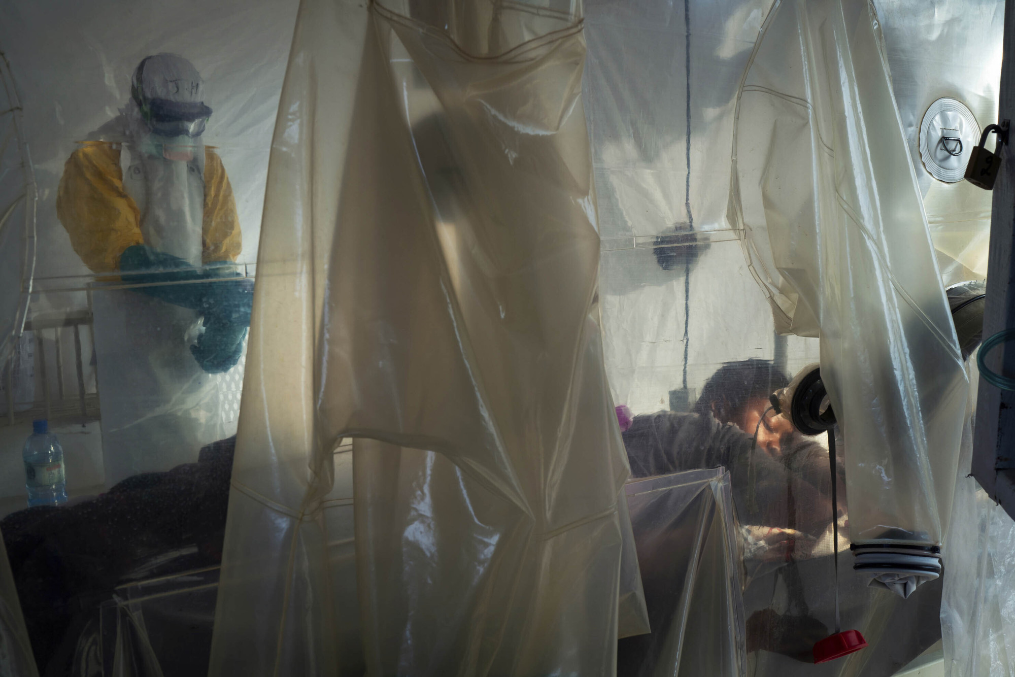 Health workers wearing protective gear check on a patient isolated in a plastic cube at an Ebola treatment center in Beni, Congo, July 13. Health authorities in Congo have halted an Ebola treatment study early with good news: Two of the four experimental drugs seem to be saving lives. More than 1,800 people have died in the African country's yearlong outbreak. | AP