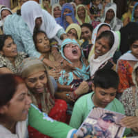 The wife of Krishan Lal, an Indian Army soldier who was killed during shooting from the Pakistan side of the border last Saturday, wails by his body in the village of Ghagriyal, in the Jammu district of Jammu and Kashmir state, on Wednesday. | AP