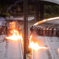 Firebombs thrown toward riot police during a protest in the Admiralty district of Hong Kong on Saturday burn after exploding. Police used water cannons to spray blue-dyed water at defiant protesters, who lobbed the projectiles at them as tensions between demonstrators and authorities escalated on. | BLOOMBERG