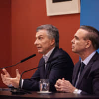 Mauricio Macri, (left) Argentina\'s president, speaks as Miguel Angel Pichetto, the leader of Peronism in Argentina\'s Senate, listens during a press conference at the Presidential Palace (Casa Rosada) in Buenos Aires on Monday. The cost of hedging Argentina\'s sovereign debt against losses soared to a multiyear high Monday after Macri was unexpectedly defeated by a landslide in a primary vote. | BLOOMBERG