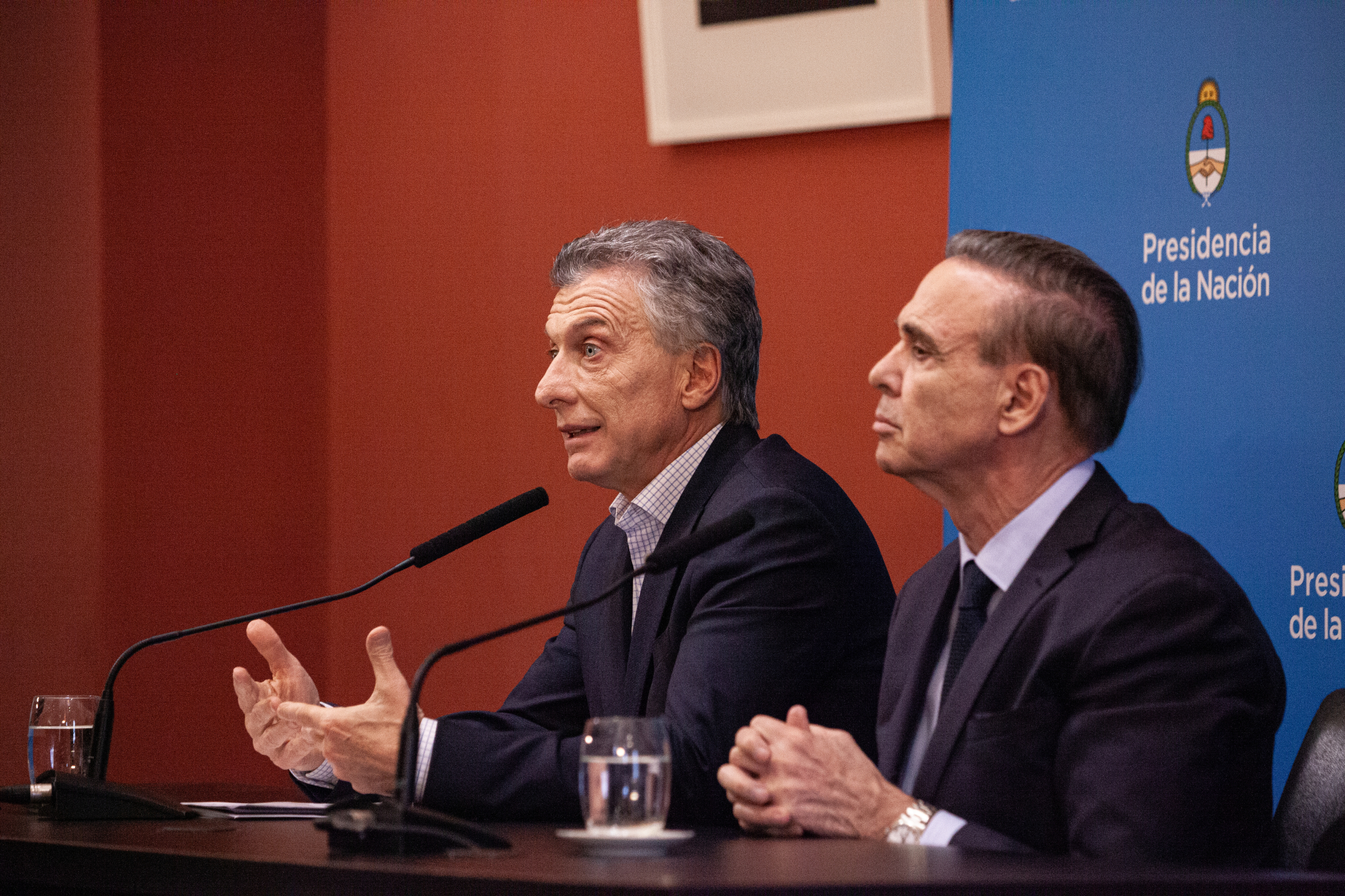 Mauricio Macri, (left) Argentina's president, speaks as Miguel Angel Pichetto, the leader of Peronism in Argentina's Senate, listens during a press conference at the Presidential Palace (Casa Rosada) in Buenos Aires on Monday. The cost of hedging Argentina's sovereign debt against losses soared to a multiyear high Monday after Macri was unexpectedly defeated by a landslide in a primary vote. | BLOOMBERG