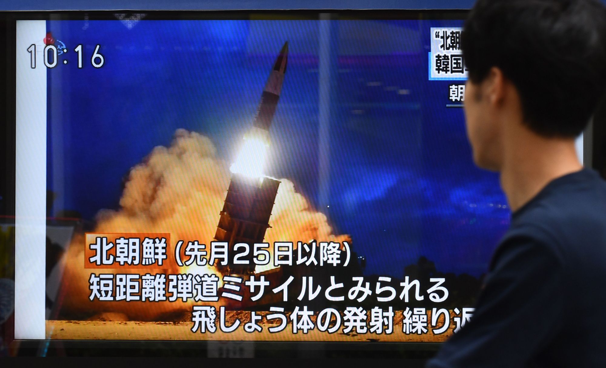 A pedestrian watches a roadside television screen in Tokyo on Friday broadcasting news about North Korea's launch of two 'projectiles' earlier in the day. | AFP-JIJI
