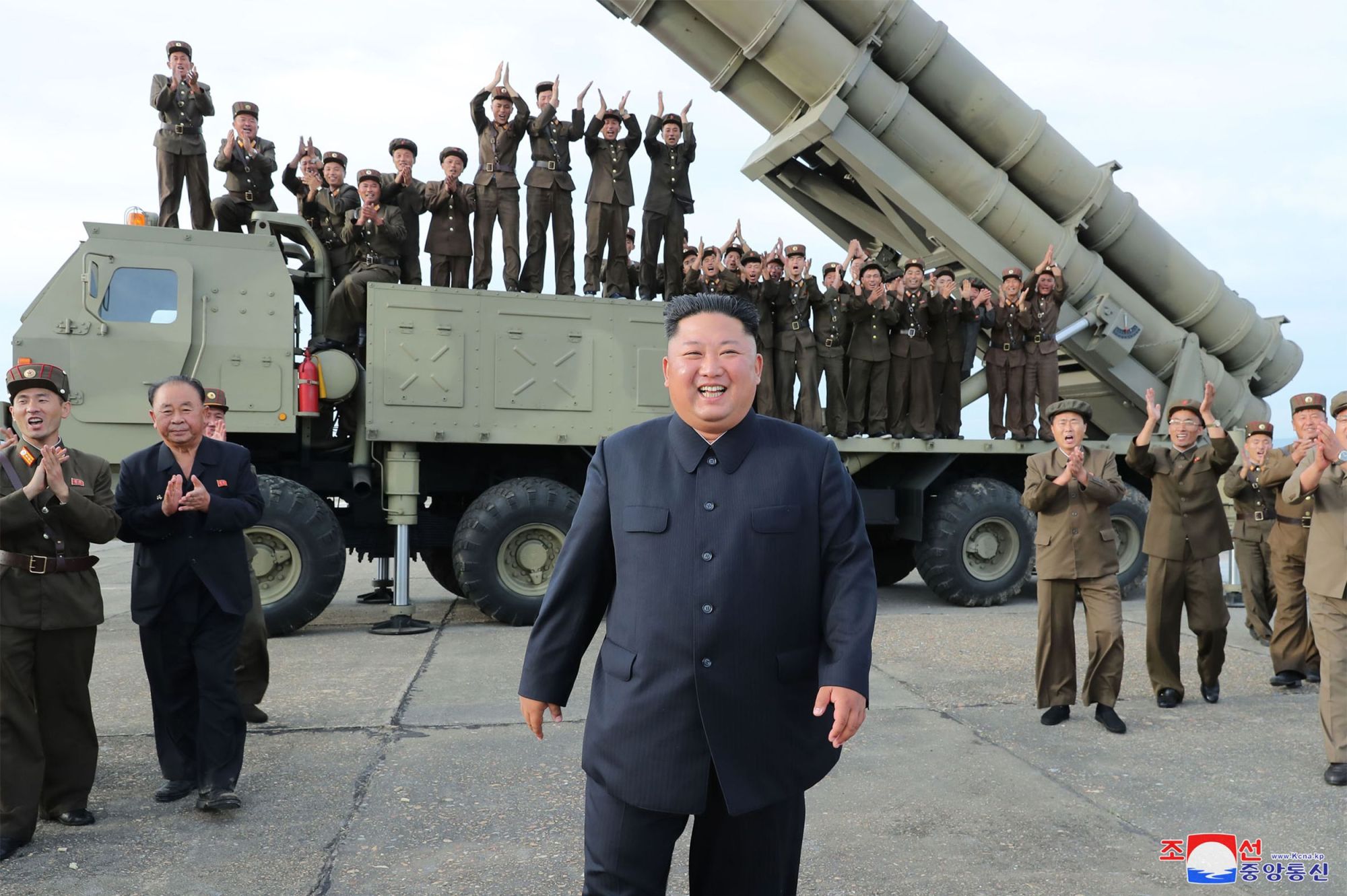 North Korean leader Kim Jong Un celebrates the test-firing of a 'newly developed super-large multiple rocket launcher' at an undisclosed location Saturday. | AFP-JIJI