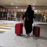 A Saudi woman walks with her luggage as she arrives at King Fahd International Airport in Dammam, Saudi Arabia, Aug. 5. | REUTERS