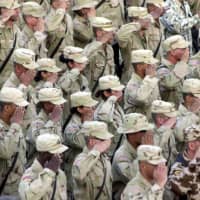 U.S. soldiers salute during a flag-lowering ceremony at Bagram Air Base in Afghanistan on Sept. 11, 2002. | AFP-JIJI