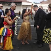 U.S. Secretary of State Mike Pompeo and his wife Susan are greeted by women with traditional mwar mwar floral wreaths as they arrive at Pohnpei International Airport in Kolonia, Federated States of Micronesia, on Monday. | AP