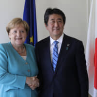 German Chancellor Angela Merkel and Prime Minister Shinzo Abe shake hands during a meeting on the first day of the G7 summit in Biarritz, France, on Saturday. | AP