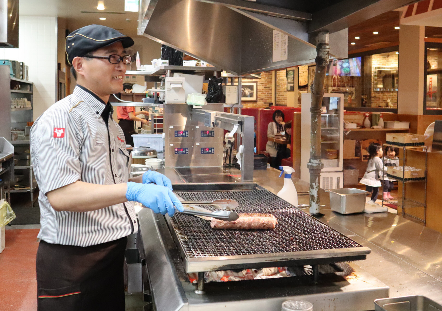 Xia Gang, a Chinese manager of a Bronco Billy restaurant in Nagoya's Moriyama Ward, grills a Hamburg steak at the restaurant. | CHUNICHI SHIMBUN
