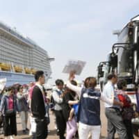 Foreign tourists walk to a sightseeing bus after arriving by cruise ship at a port in Sakaiminato, Tottori Prefecture, in May 2016. | KYODO