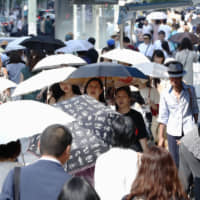 Pedestrians use parasols to shield themselves from the hot sun in Tokyo\'s Ginza district on Wednesday. | KYODO