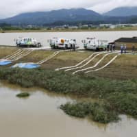 Officials work to drain water in Omachi, Saga Prefecture, on Thursday after torrential rain caused flooding in many areas. | KYODO