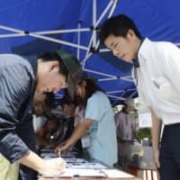 A man who lost his wife and daughter in a car crash in Toshima Ward, Tokyo, in April, on Saturday collects signatures after organizing a petition demanding the elderly driver be punished. | KYODO