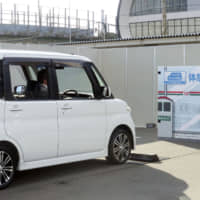 A minivehicle equipped with sensors to avoid collisions stops before an obstacle in Osaka. | KYODO