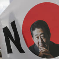 A protester holds a sign during a rally in Seoul Thursday against Japanese moves to tighten exports to South Korea. | AP