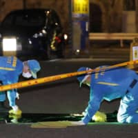 Police officers investigate a crime scene where a man was stabbed Friday evening in Yokohama. | KYODO