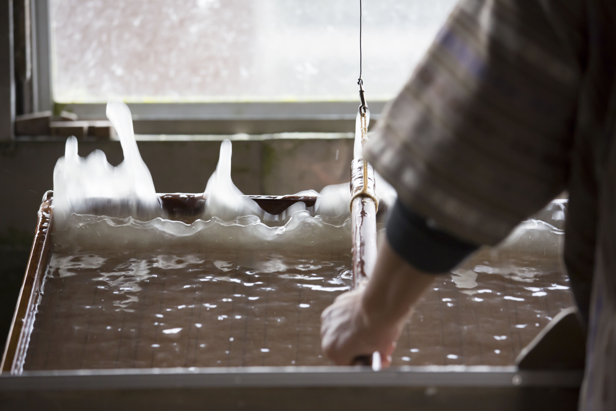 Just like great-great-great-grandma used to make: A washi (handmade Japanese paper) artisan mixes and scoops paper pulp using a suketa (bamboo-scrim mold). | MASASHI KUMA