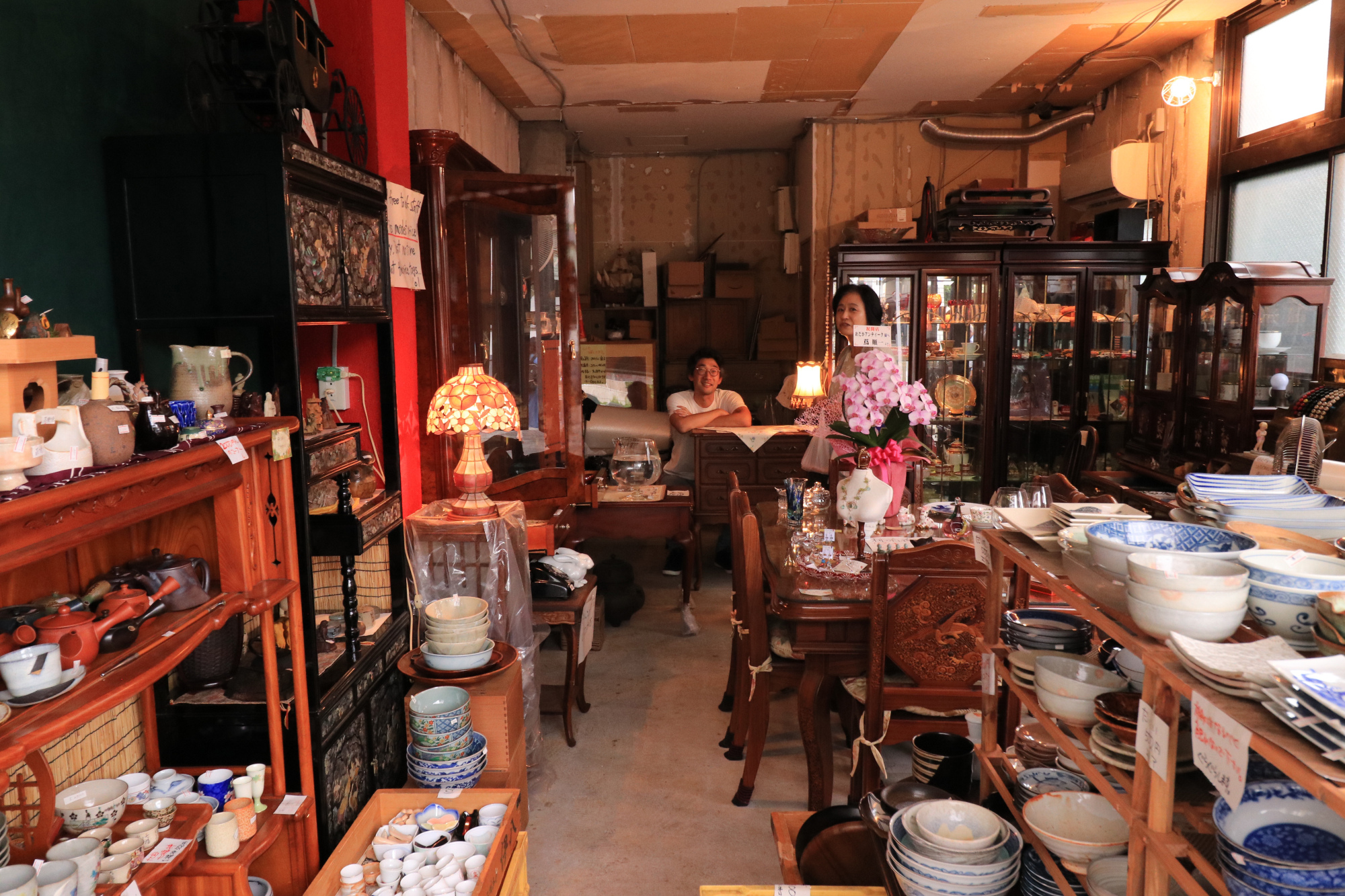 Yoichiro Kumano of Medaka Antiques chats with Mon-Naka resident Junko Toyama. | KIT NAGAMURA