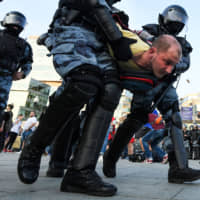 Riot police detain a protester during an unauthorized rally in Moscow demanding independent and opposition candidates be allowed to run for office in local election in September. | AFP-JIJI