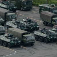 Trucks and armored personnel carriers are seen parked in Shenzhen, bordering Hong Kong, on Aug. 16. | AFP-JIJI