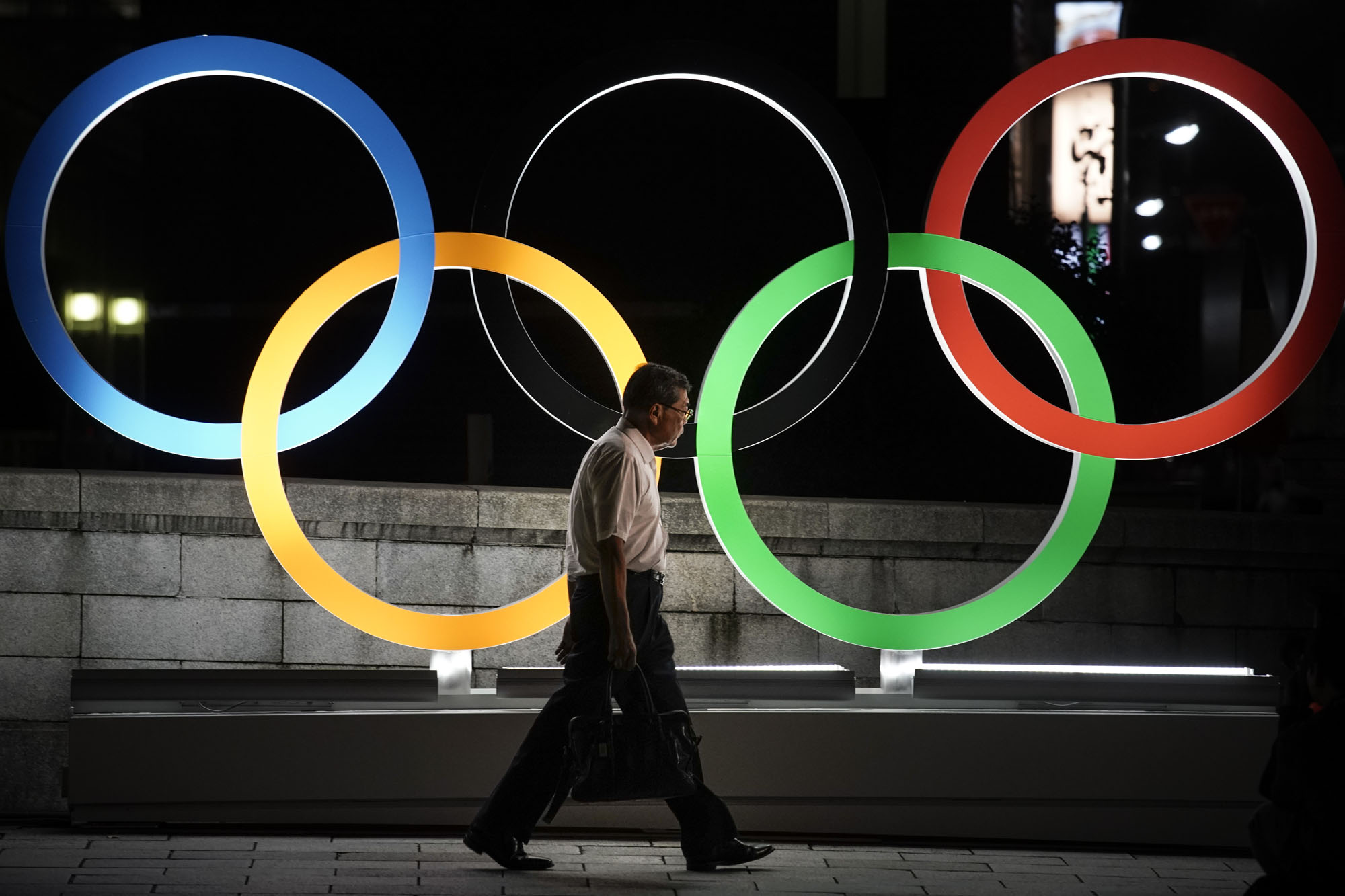 A man walks by a display of the Olympic rings in Tokyo on July 23. | AP
