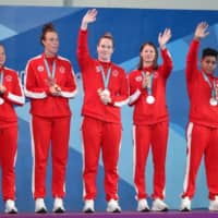 Canada\'s women\'s water polo team celebrates on the podium after winning the silver medal at the Pan American Games in Lima, Peru, on Saturday. The team qualified for the Tokyo Olympics by reaching the final, which it lost to the United States. | REUTERS