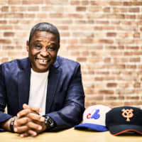 Former Central League MVP Warren Cromartie poses with the hats of his former teams, the Yomiuri Giants (right) and Montreal Expos. | COURTESY OF WARREN CROMARTIE