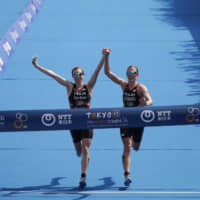 Britain\'s Georgia Taylor-Brown (left) and Jessica Learmonth hold hands as they cross the finish line during a women\'s triathlon test event at Odaiba Marine Park on Thursday. The pair was disqualified for deliberately finishing together. | AP
