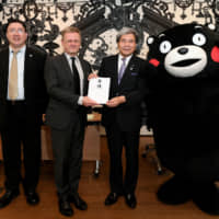 French Ambassador Laurent Pic (second from left) and Frederic Mazenq (left), a spokesman for the France Tourism Development Agency, receive a donation toward the reconstruction of Notre Dame Cathedral, which was severely damaged in a fire, from Kumamoto Gov. Ikuo Kabashima (second from right) and Kumamon, Kumamoto Prefecture\'s official mascot, during a ceremony at the French Embassy on July 25. | YOSHIAKI MIURA