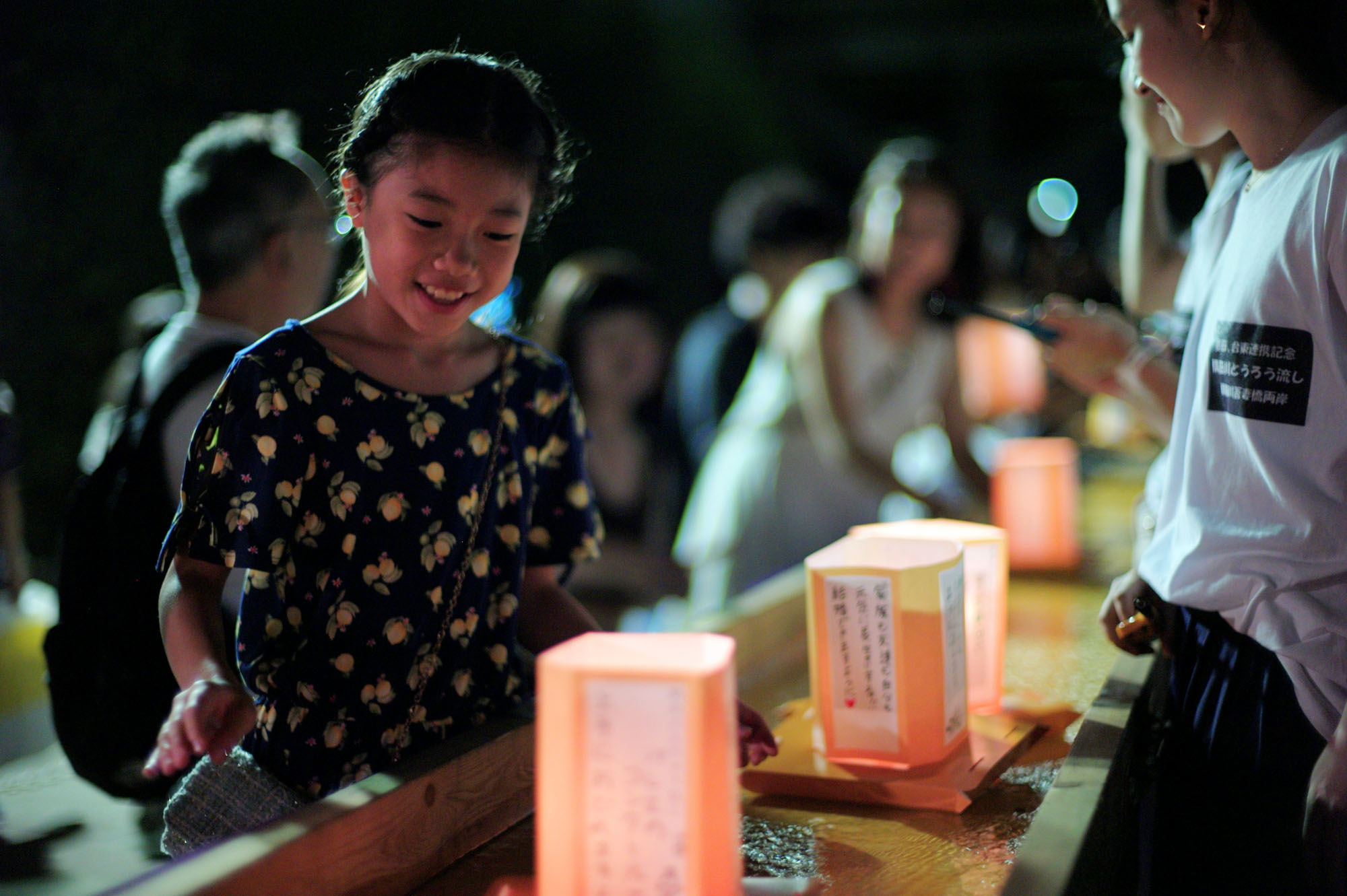 A girl looks at a lantern to be floated on the Sumida River at the annual Toro Nagashi Festival in Tokyo's Sumida Ward on Saturday evening. The festival began in 1946 to honor the war dead, especially the masses of people who drowned in the river while fleeing the devastating firebombings of Tokyo. In recent times, people inscribe wishes on the lanterns. | RYUSEI TAKAHASHI