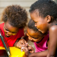 Young girls playing on a digital tablet. | GETTY IMAGES