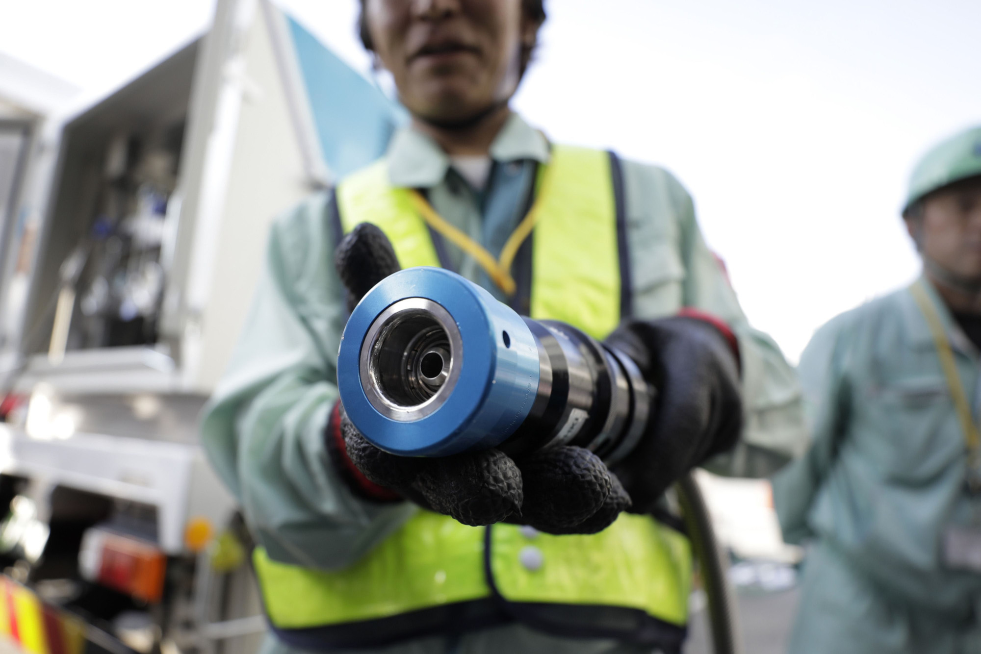 A worker shows off a hydrogen refueling hose during a demonstration at a hydrogen station in Yokohama in 2017. | BLOOMBERG