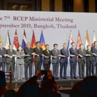 Participants in the RCEP Ministerial Meeting join hands in Bangkok on Sunday. | KYODO