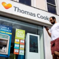 Pedestrians walk past a Thomas Cook travel agent\'s shop in London in mid-July. The tour operator has confirmed it is seeking &#163;200 million in extra funding as it attempts to prevent its collapse. | AFP-JIJI