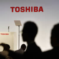 Reporters gather at a news conference at Toshiba\'s headquarters in Tokyo last November. On Monday, the electronics and energy conglomerate said it completed the sale of its liquefied natural gas operation in the United States to French oil giant Total SA. | KYODO