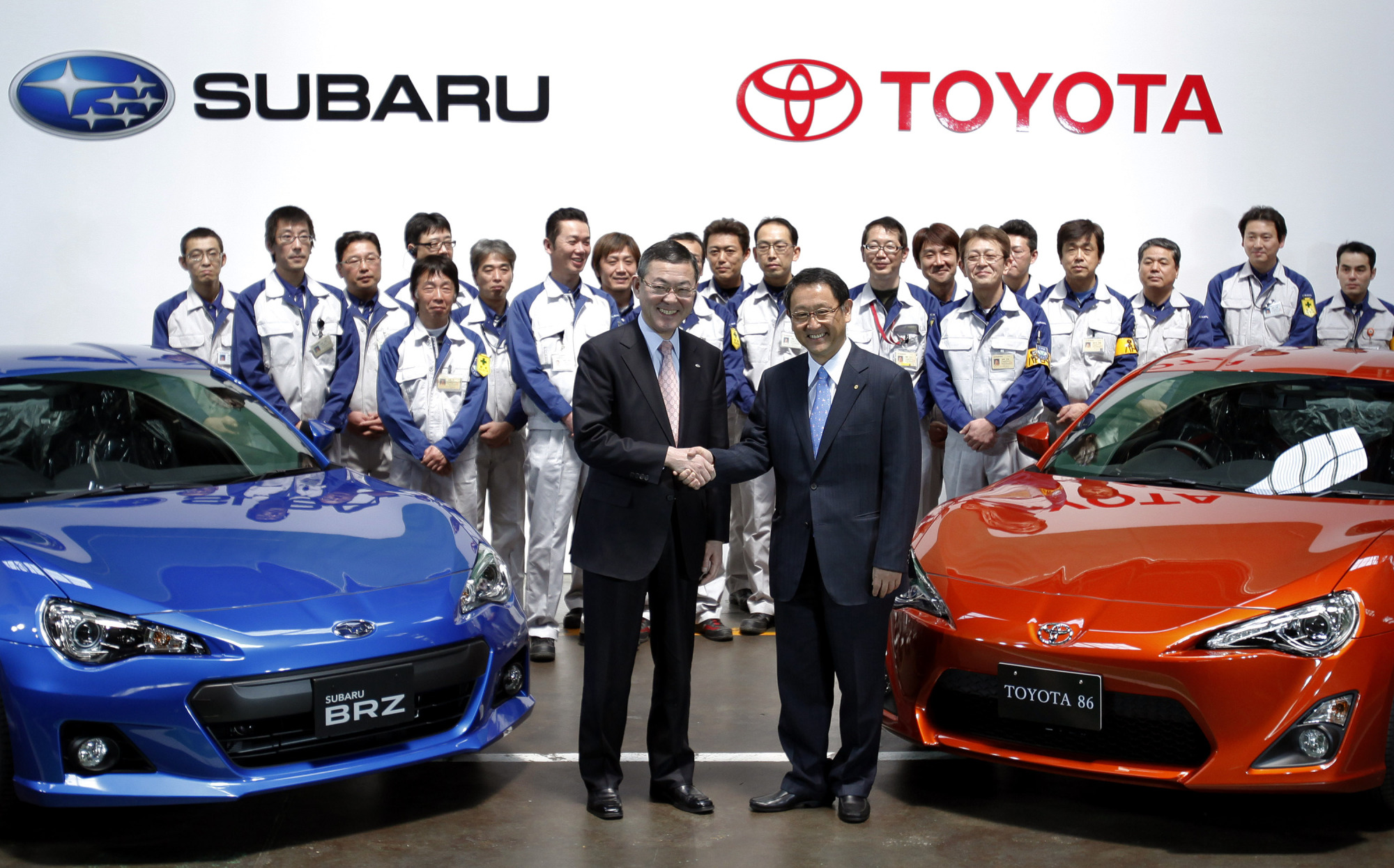 Former Fuji Heavy Industries Ltd. President Yasuyuki Yoshinaga (left) and Toyota Motor Corp. President Akio Toyoda shake hands during a line-off ceremony at Fuji Heavy's main plant in Ota, Gunma Prefecture, in 2012. Fuji Heavy is now known as Subaru Corp. | BLOOMBERG