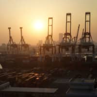 Gantry cranes stand over stacked containers at a shipping terminal in Yokohama on Aug. 17. | BLOOMBERG