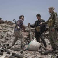 Fighters from a militia known as the Security Belt, which is funded and armed by the United Arab Emirates, discuss launching a mortar toward Houthi rebels in an area called Moreys on the front line in Yemen\'s Dhale province Aug. 5. | AP