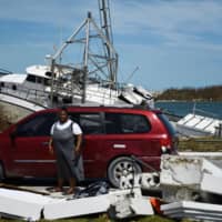 Residents pass damage caused by Hurricane Dorian on Thursday in Marsh Harbour, Great Abaco Island in the Bahamas. | AFP-JIJI