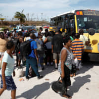 People try to get on a bus at Marsh Harbour Healthcare Center after hurricane Dorian hit the Abaco Islands in Marsh Harbour, Bahamas, Thursday. | REUTERS