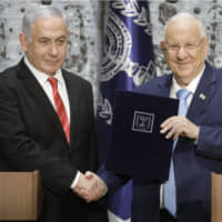 Israeli President Reuven Rivlin (right) shakes hands with Israeli Prime Minister Benjamin Netanyahu in Jerusalem Wednesday. The office of the president says Netanyahu has been given the task of forming a new government. | AP