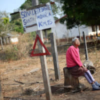 A resident looks on in the Santa Monica community in Concepcion, Bolivia, Saturday. The sign reads, \"Disaster zone. Santa Monica, Km. 15.\" | REUTERS