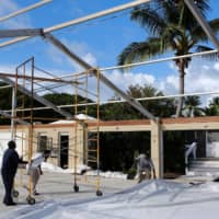 Workers remove textile roofing from a structure before the arrival of Hurricane Dorian in the Great Abaco island town of Marsh Harbour, Bahamas, on Saturday. | REUTERS