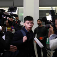 Hong Kong\'s pro-democracy activist Joshua Wong is surrounded by journalists after arriving at Tegel Airport in Berlin, Germany, on Monday. | REUTERS