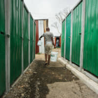 A resident carries plastic containers of water in the Imizamo Yethu township outside Cape Town on Nov. 13, 2017. | BLOOMBERG