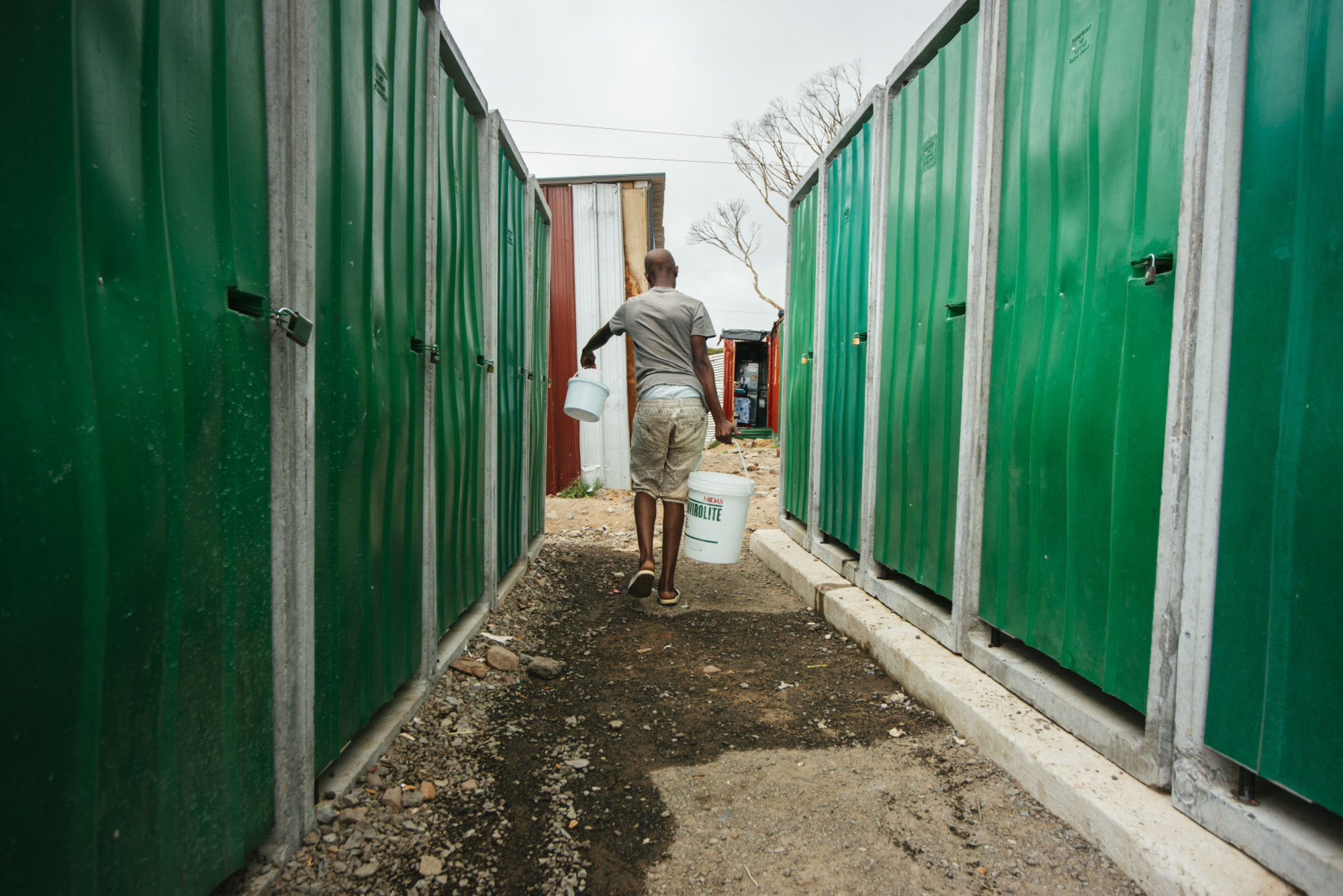 A resident carries plastic containers of water in the Imizamo Yethu township outside Cape Town on Nov. 13, 2017. | BLOOMBERG
